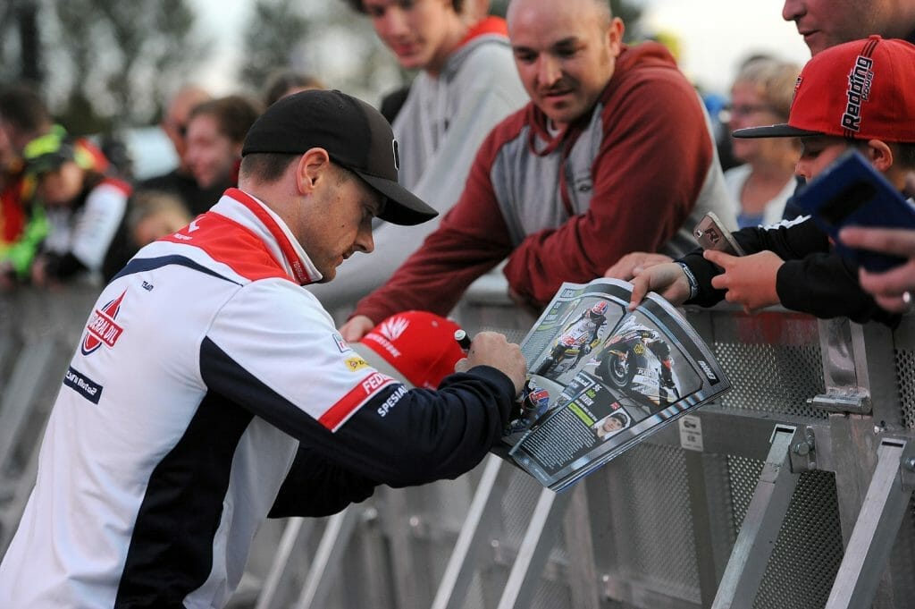 Sam Lowes signs an autograph for a young fan