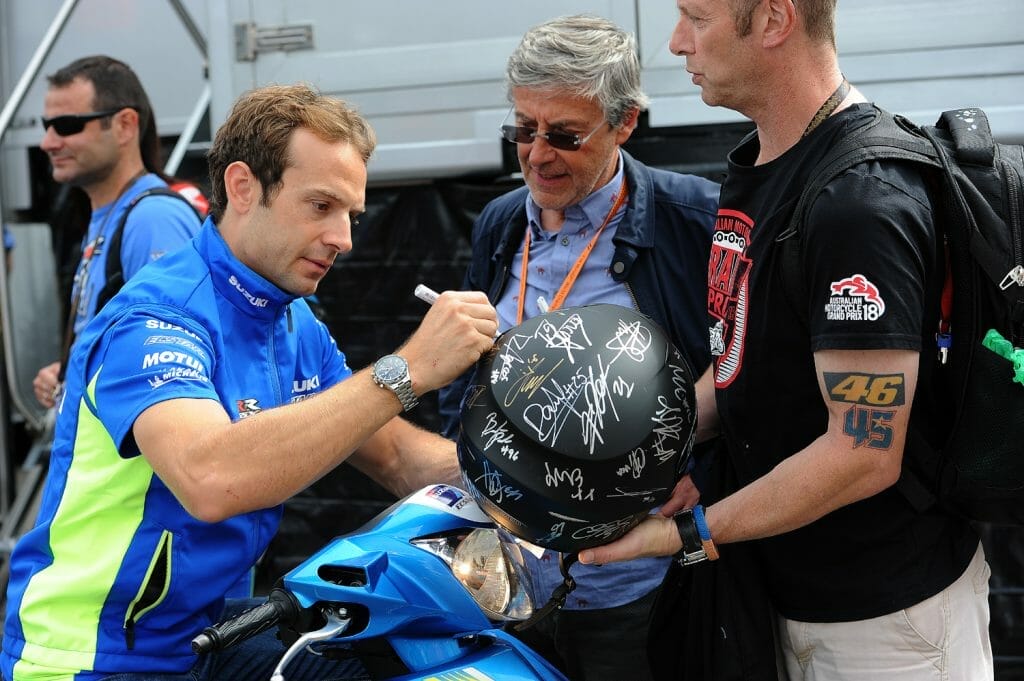 Sylvain Guintoli signs a helmet for a fan