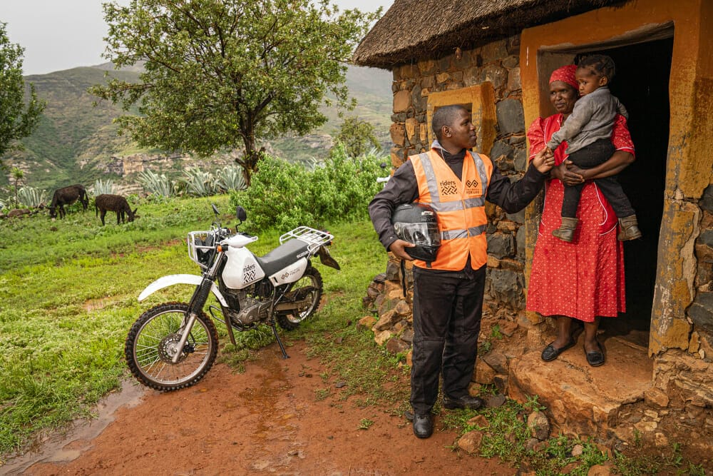 Motorcycle health worker in community with mother and baby,Lesotho, 2020